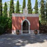 Ma le sorprese non sono finite, visto che sul lato opposto del giardino scoviamo una chiesetta con merlatura bianca e un fastigio goticheggiante con un bassorilievo religioso